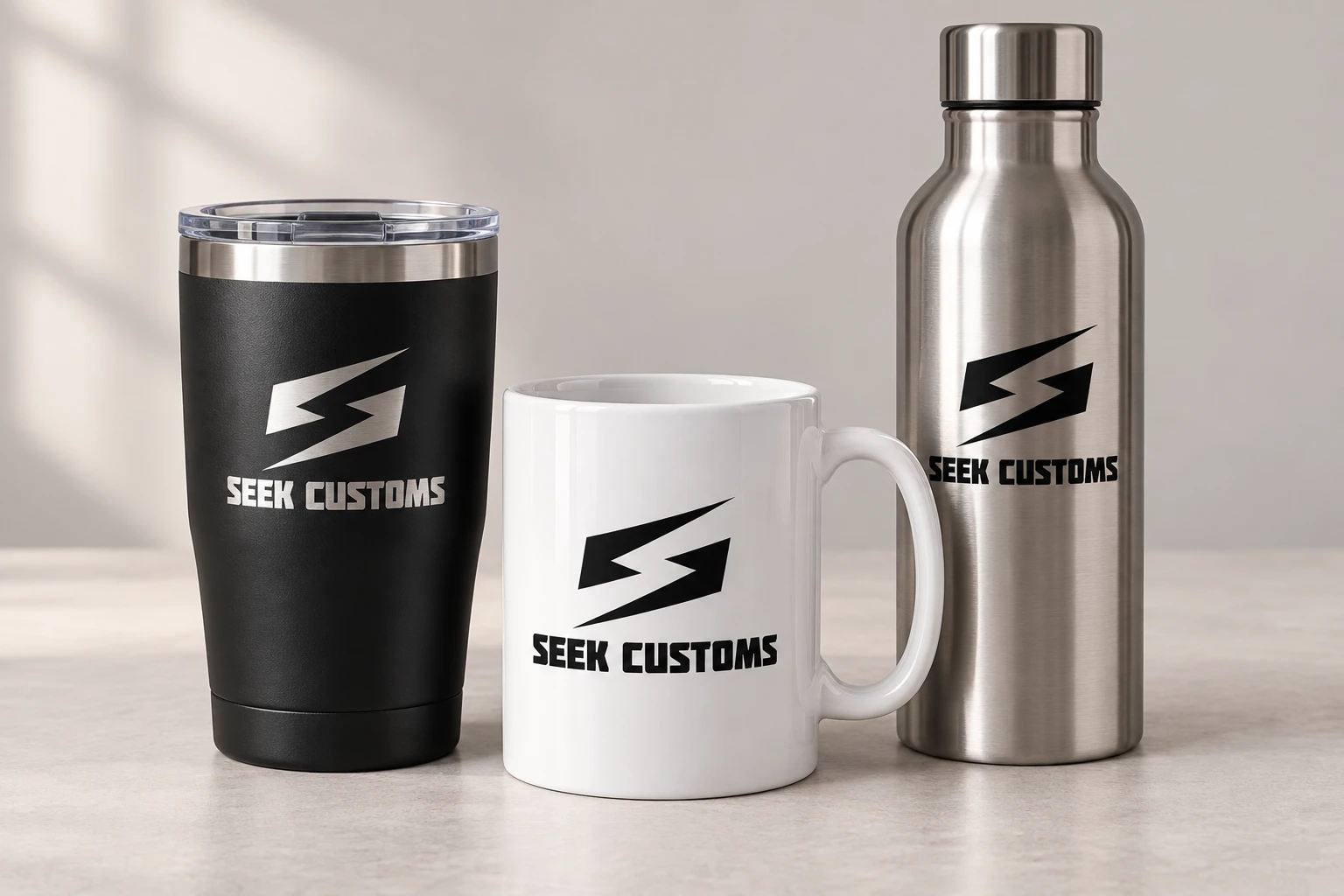 A tumbler, mug, and water bottle branded with Seek Customs logos